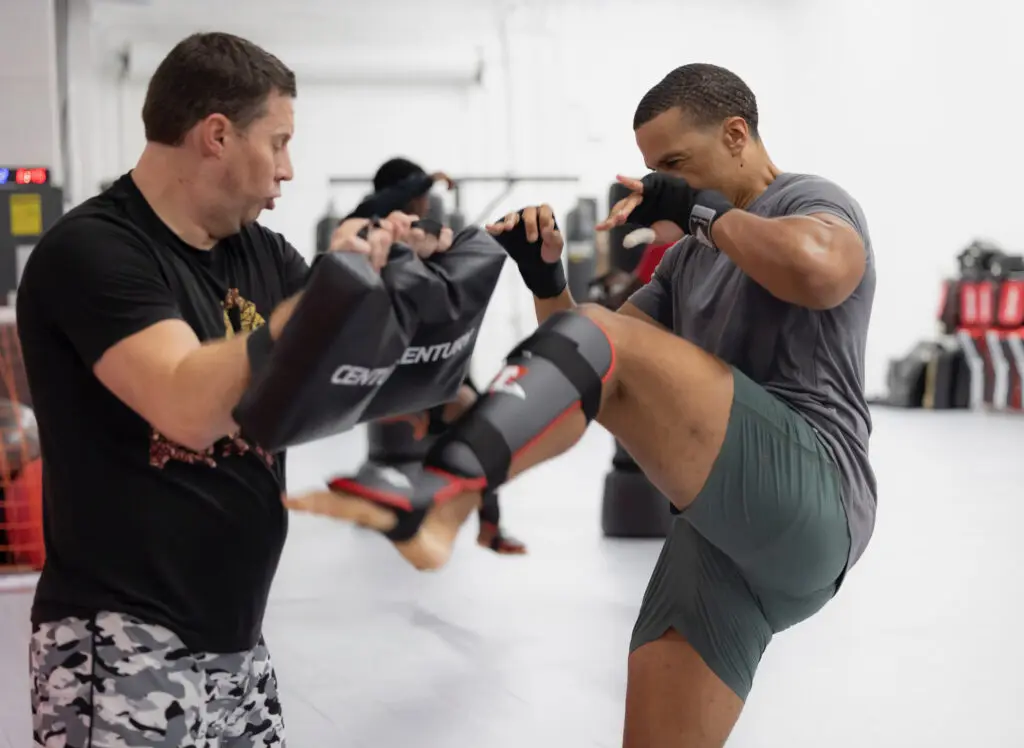 Two adults driving knees and kicks into the pads during a Muay Thai and Boxing class at ATT Winter Garden